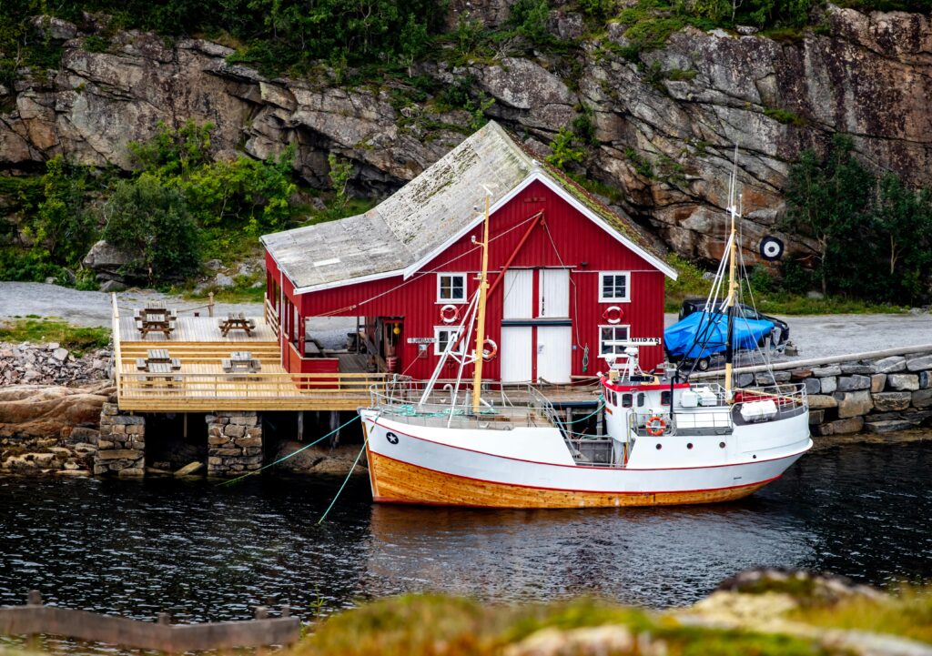 Scenic view of a red boathouse with fishing boat in Bessaker, Norway.